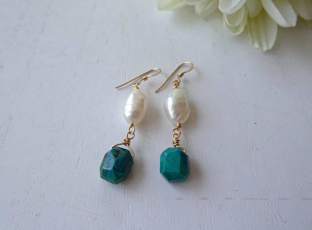 Pair of earrings with green beads and pearls on a white background