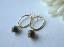 Load image into Gallery viewer, Gold hoop earrings with gray beads on a white surface with flowers in the background