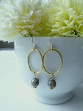Load image into Gallery viewer, Gold hoop earrings with gray beads in front of light green flowers.