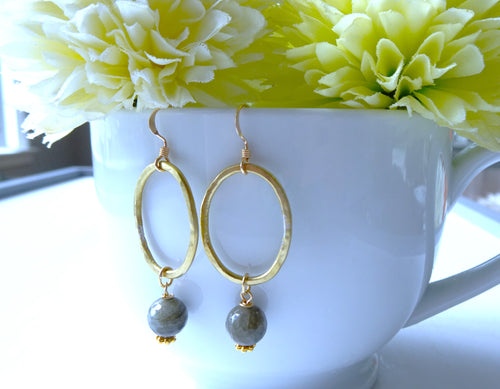 Gold hoop earrings with labradorite on a white cup with yellow flowers