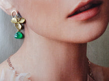Load image into Gallery viewer, Close-up of a person wearing gold earrings with green gemstones.