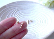 Load image into Gallery viewer, Gold Bar earrings held between fingers on a white surface